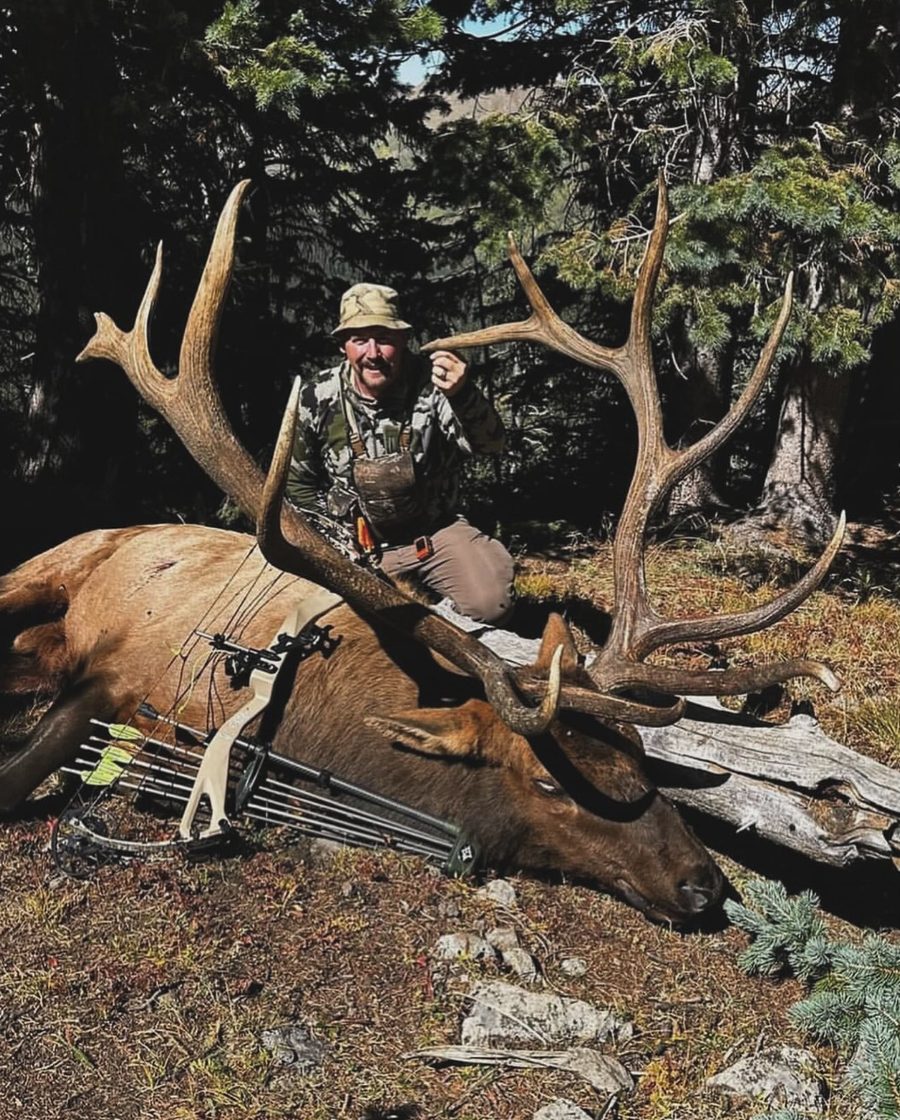 Elk caller Joel Turner kneeling behind a 366-inch bull elk